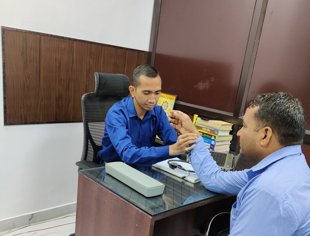 Prof. Dr. Hitendra Chiranji Mankele examining a patient's pulse during an Ayurvedic consultation